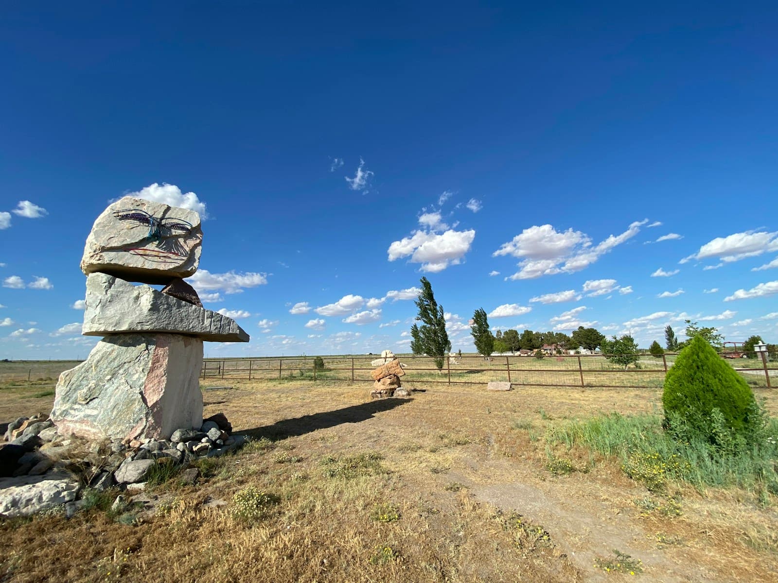 Stone cairn monument in dry rural landscape under blue sky with clouds